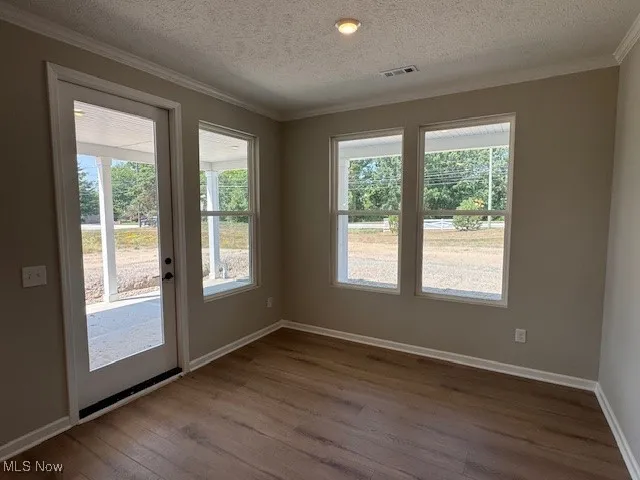 Entryway featuring dark wood finished floors, crown molding, and a textured ceiling