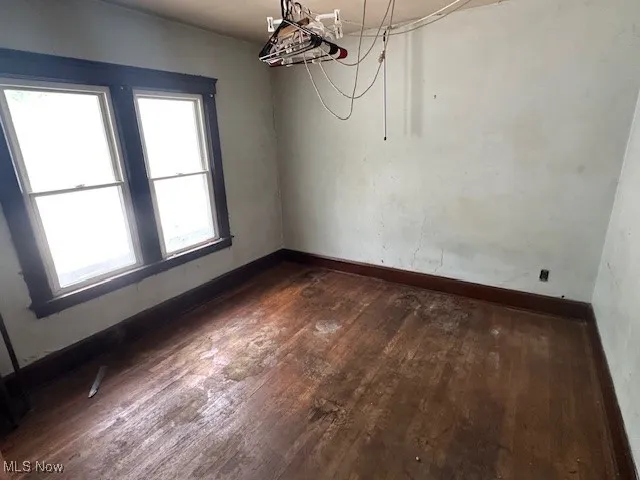 Unfurnished room featuring dark wood finished floors and baseboards
