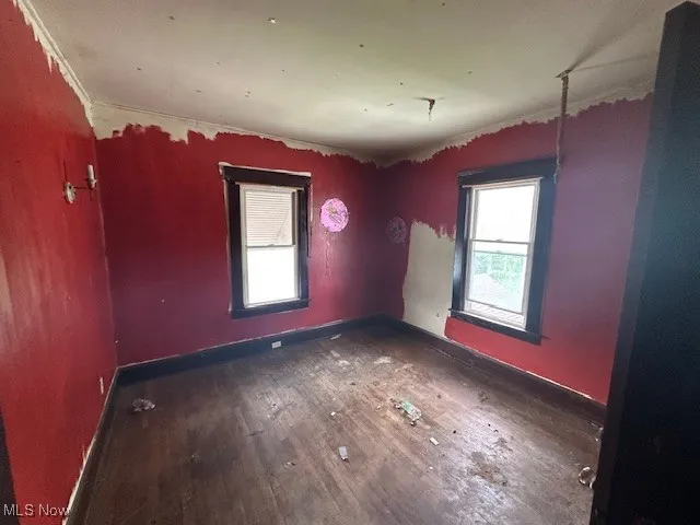 Unfurnished room with hardwood / wood-style floors, baseboards, and crown molding