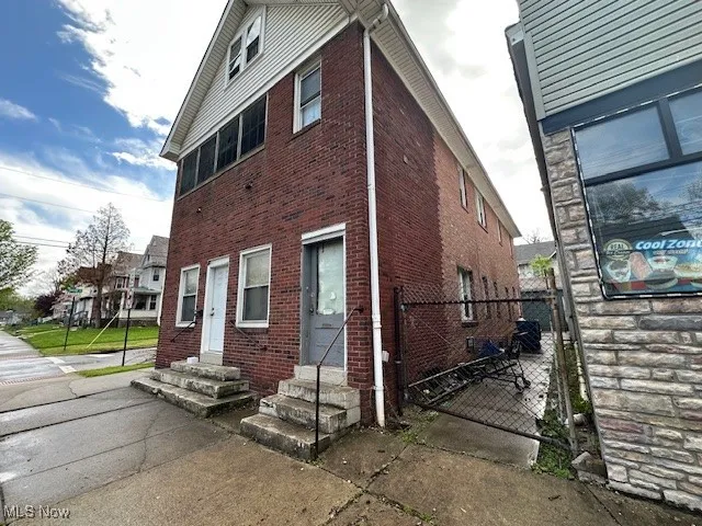 View of home's exterior featuring brick siding, entry steps, and a gate