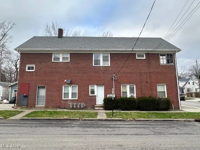 View of front of house featuring a chimney and brick siding