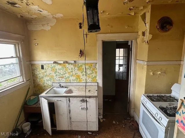 Kitchen featuring white gas range and a sink