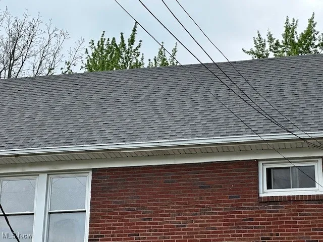 Exterior view of roof with shingles and brick siding