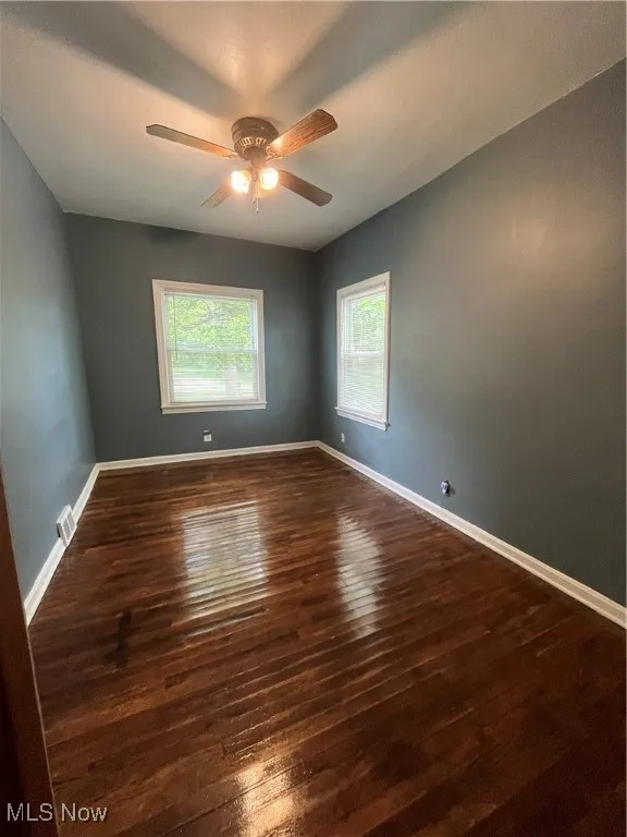 Spare room featuring dark wood finished floors, ceiling fan, and baseboards