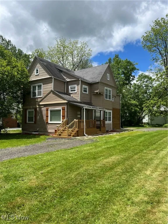View of front of house with a front lawn and a shingled roof