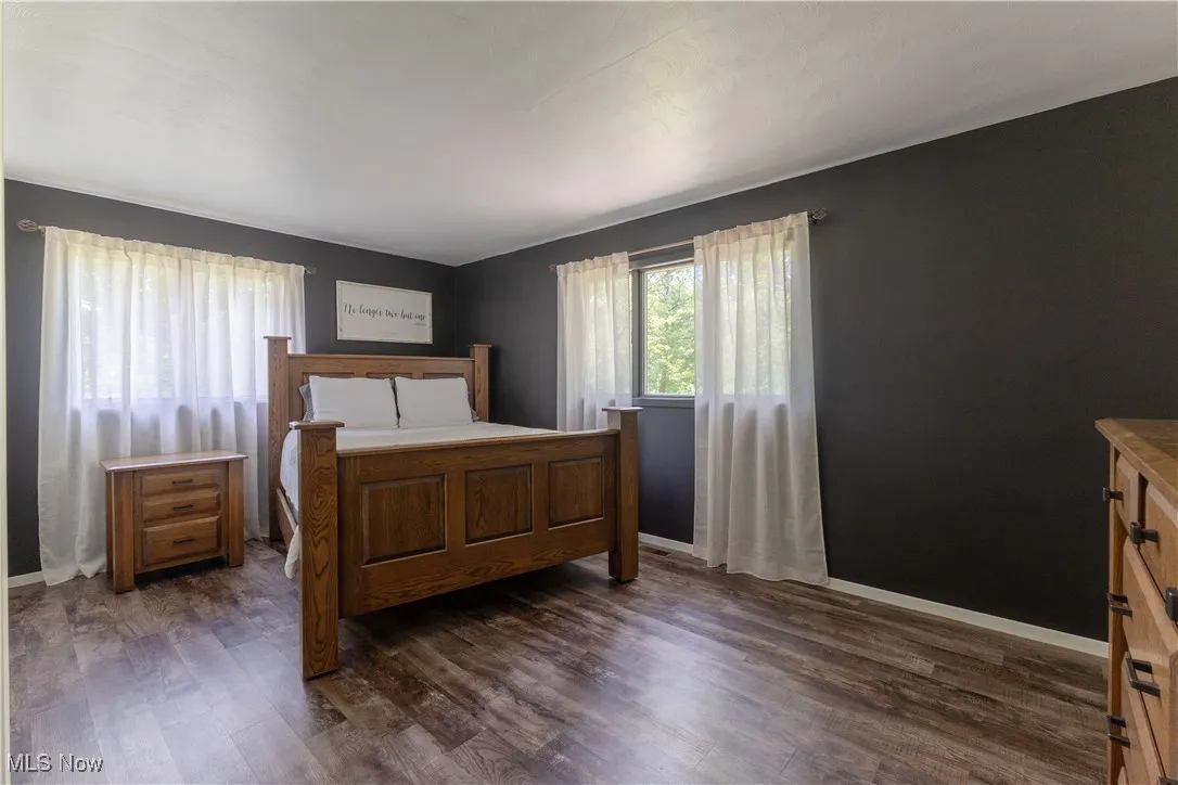 Bedroom featuring dark wood-style flooring and baseboards