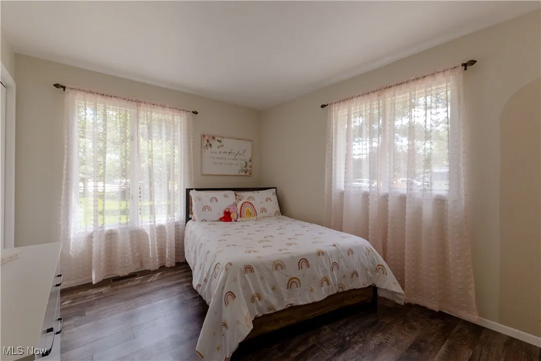 Bedroom featuring multiple windows, wood finished floors, and arched walkways