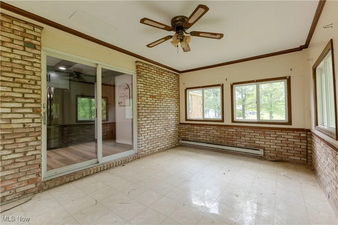 Unfurnished sunroom with a baseboard radiator, a ceiling fan, and plenty of natural light