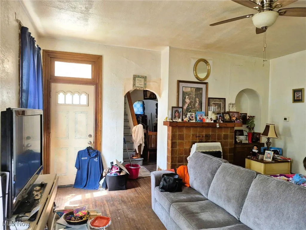Living room with wood finished floors, a ceiling fan, and arched walkways