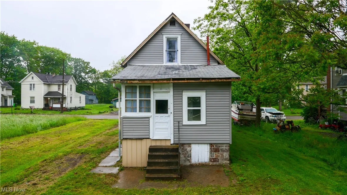Rear view of house with entry steps and a lawn