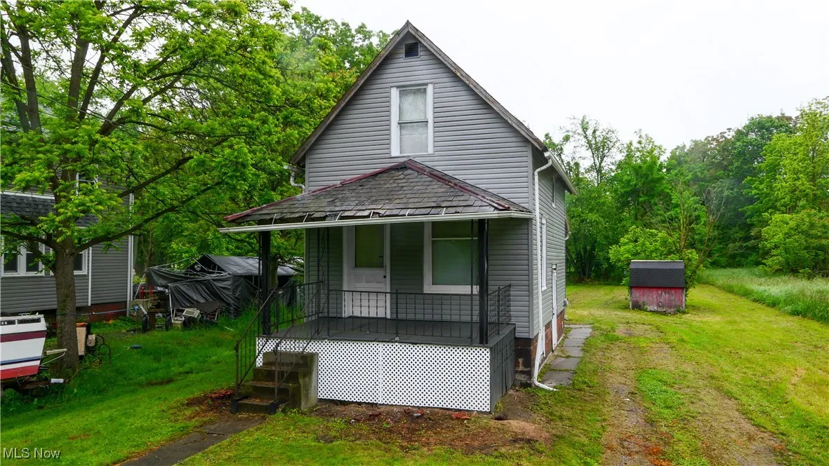 Rear view of house with covered porch and a lawn