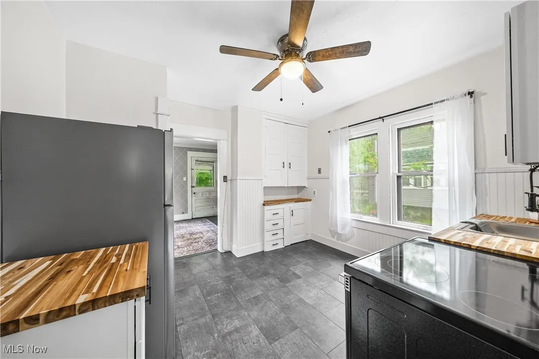 Kitchen featuring freestanding refrigerator, electric range, butcher block countertops, and white cabinetry