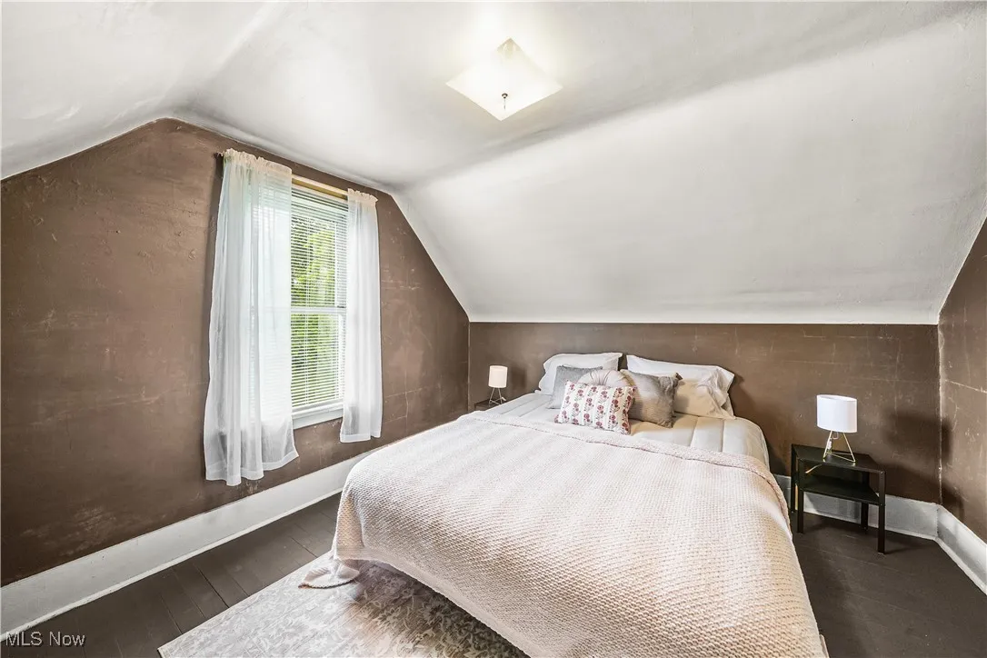 Bedroom with lofted ceiling, wood finished floors, and baseboards