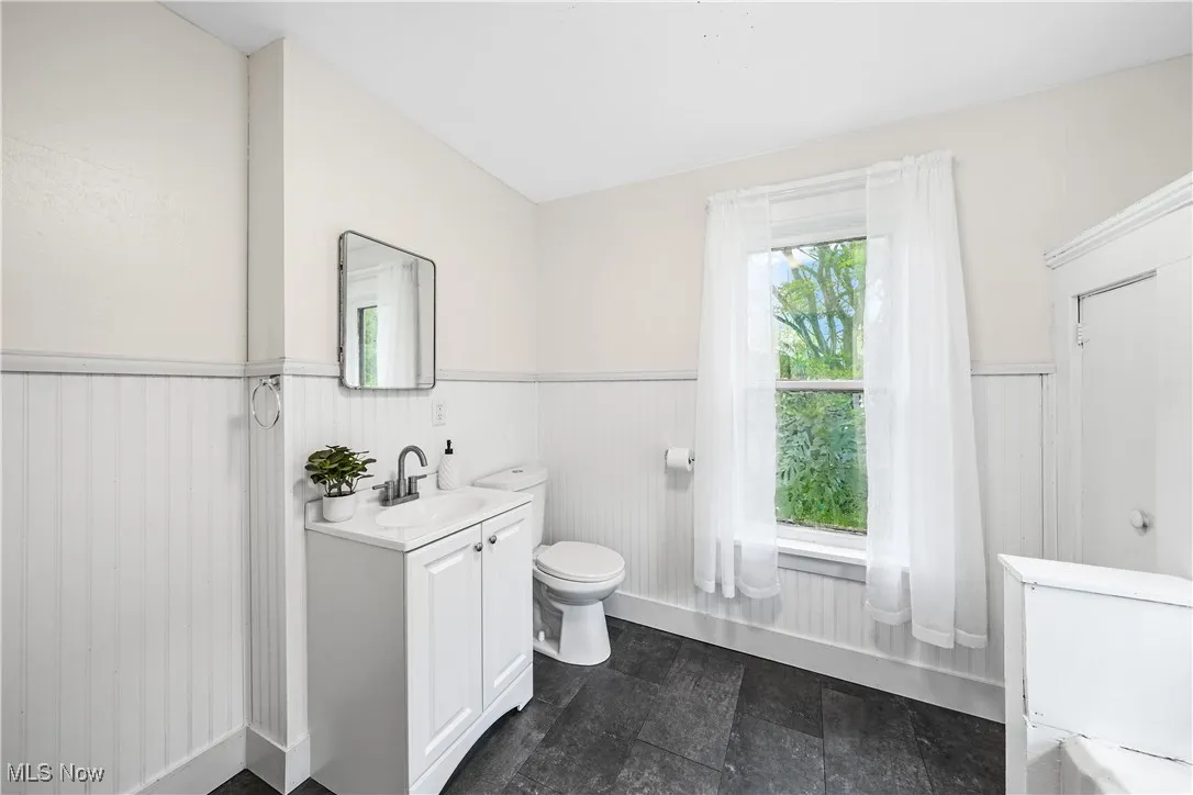 Bathroom with toilet, wainscoting, and vanity