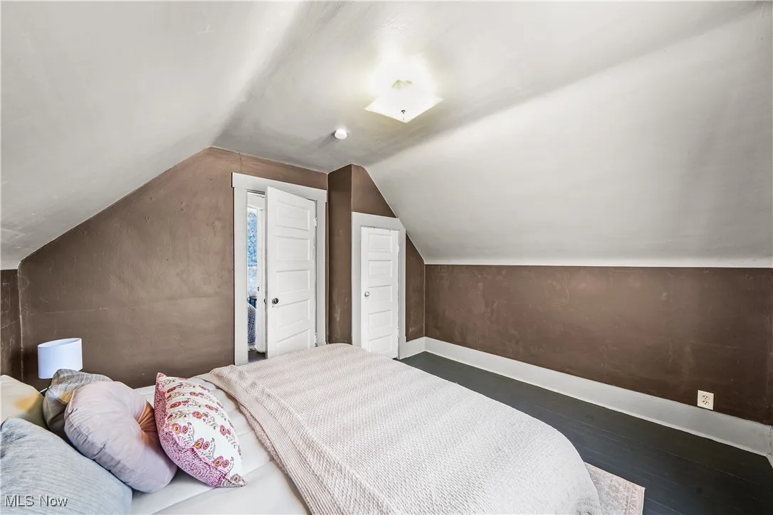 Bedroom featuring baseboards, wood finished floors, and vaulted ceiling