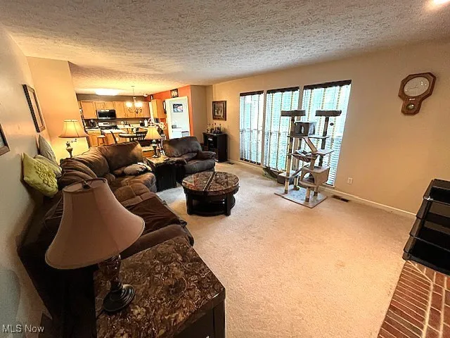 Carpeted living area featuring a textured ceiling and baseboards