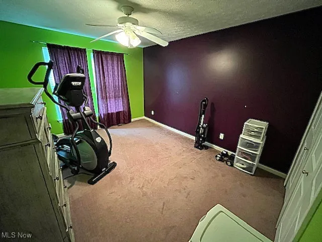 Workout area with carpet, ceiling fan, baseboards, and a textured ceiling