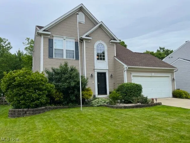Traditional-style home with a garage, driveway, and a front lawn