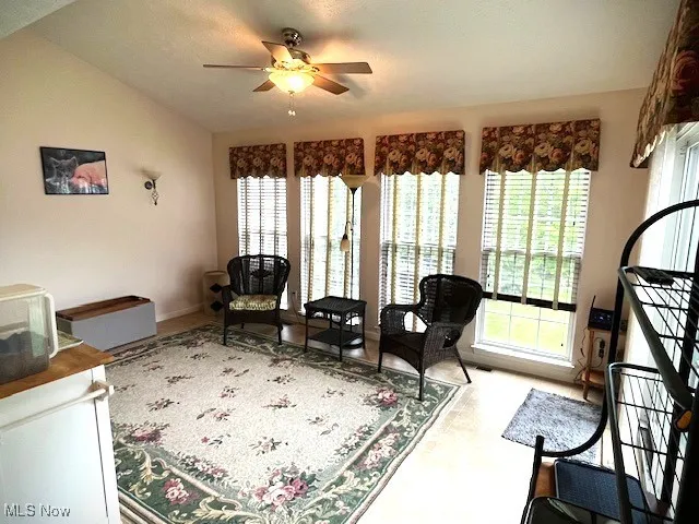 Living room featuring plenty of natural light, a ceiling fan, lofted ceiling, and baseboards