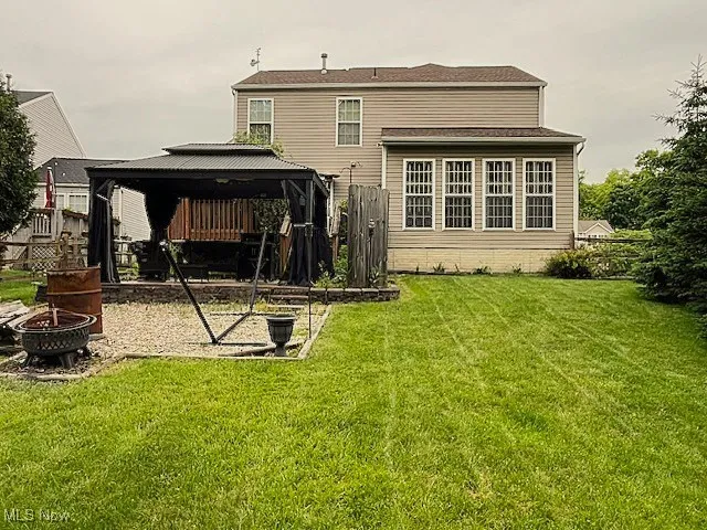 Back of property featuring a gazebo and an outdoor fire pit