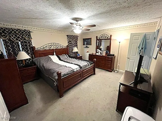 Bedroom featuring light colored carpet, a textured ceiling, and a ceiling fan