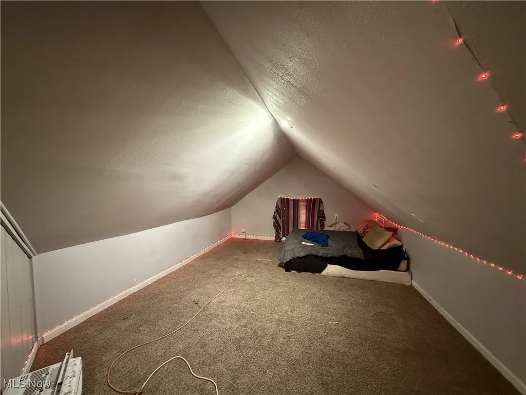 Unfurnished room with carpet, a textured ceiling, lofted ceiling, and baseboards