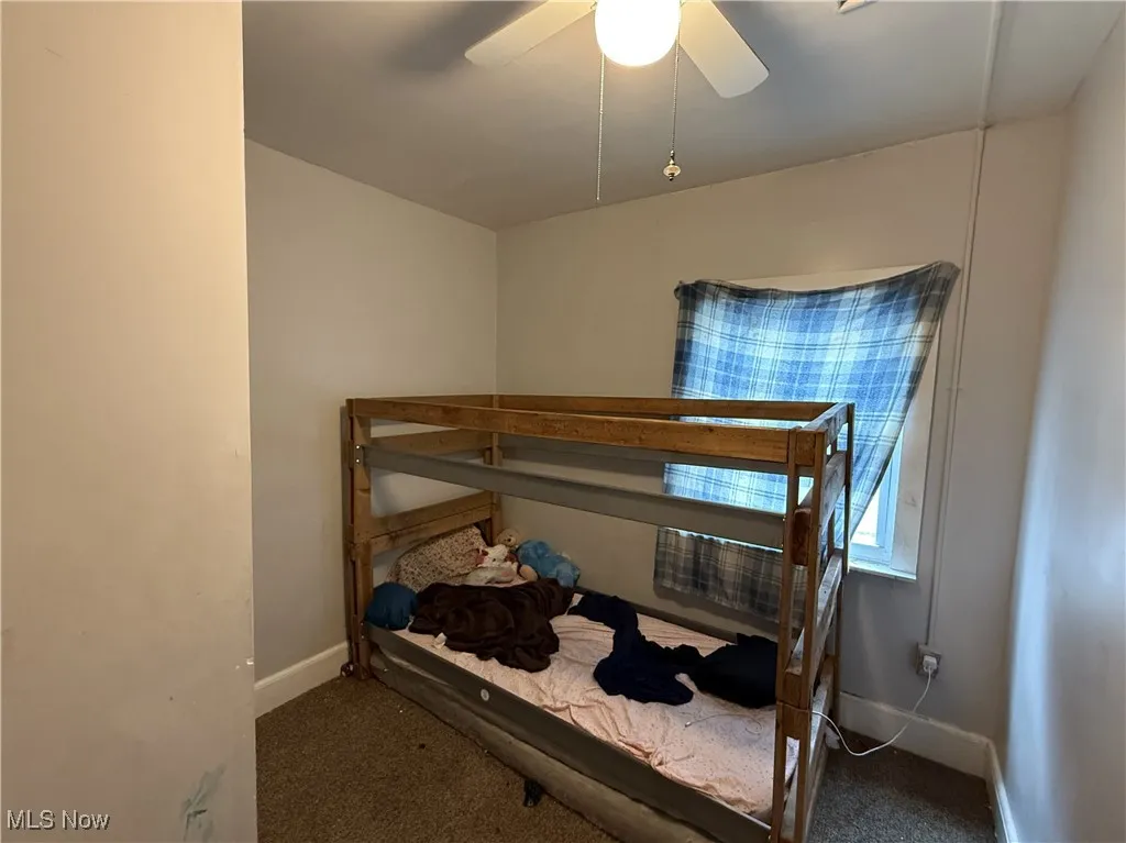 Carpeted bedroom featuring ceiling fan and baseboards