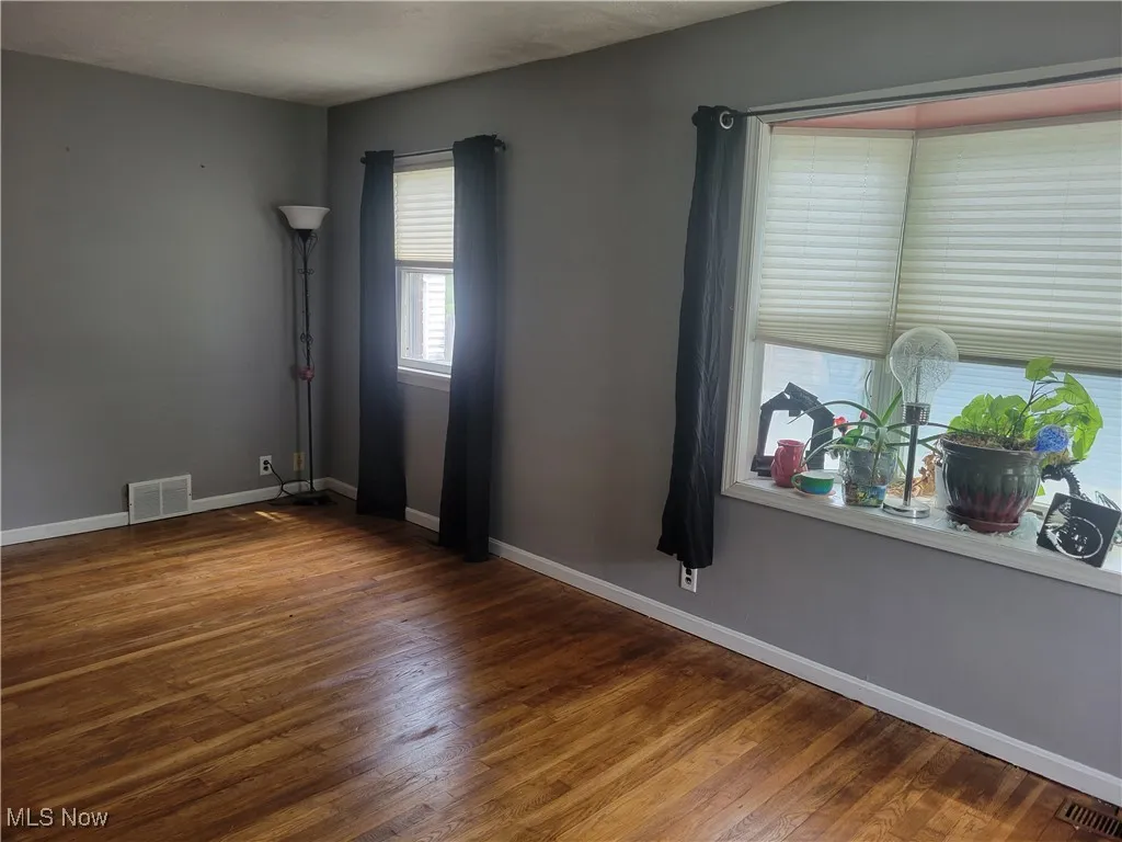 Unfurnished room with wood finished floors and baseboards