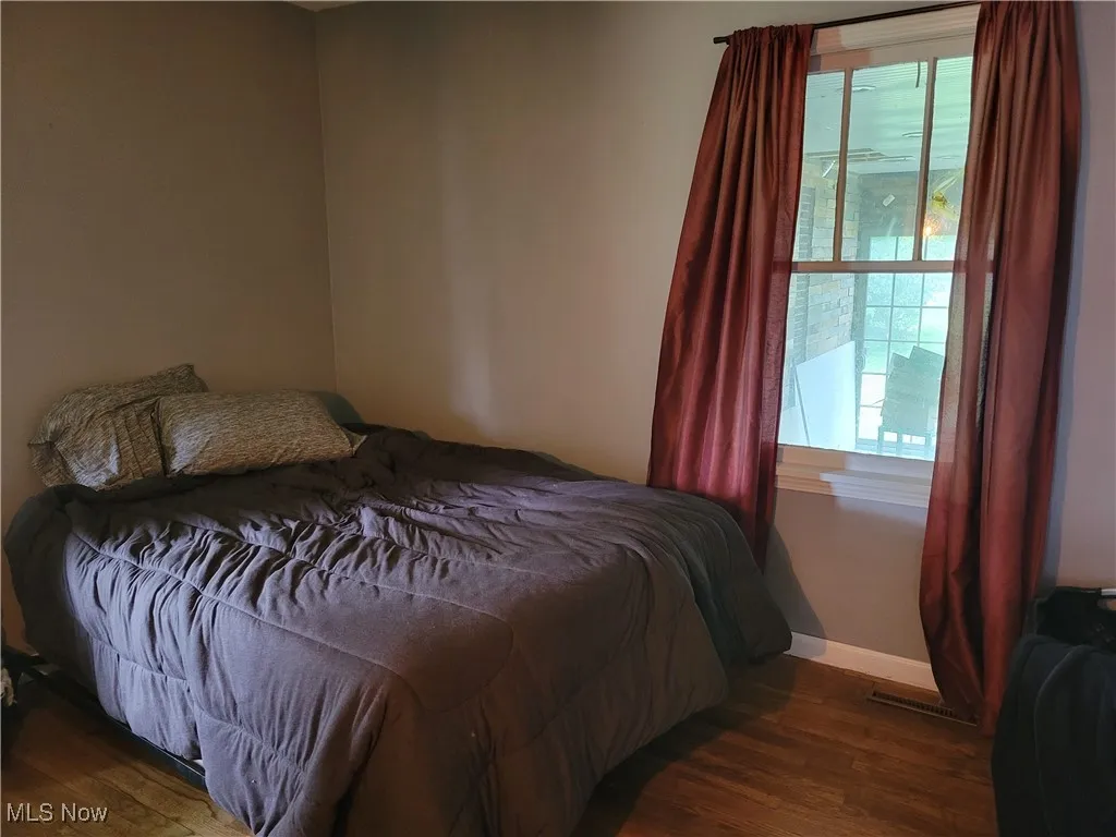 Bedroom with multiple windows, wood finished floors, and baseboards