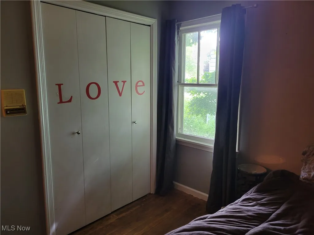 Bedroom with dark wood-style flooring, baseboards, and a closet