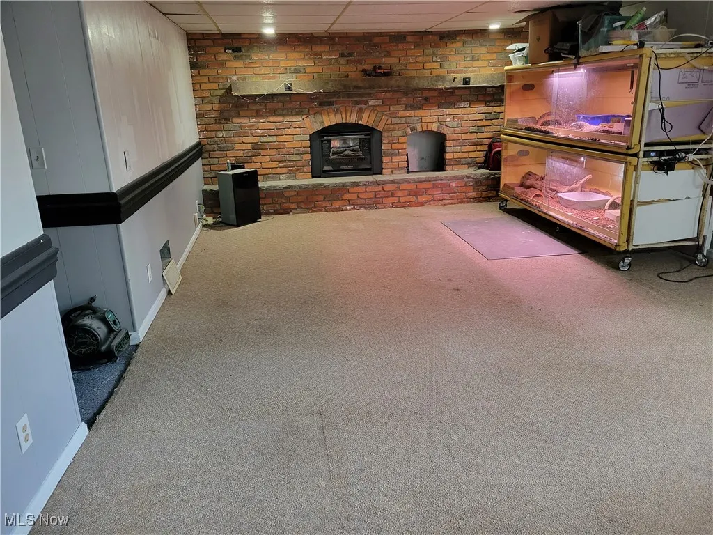 Carpeted living area featuring baseboards and a fireplace