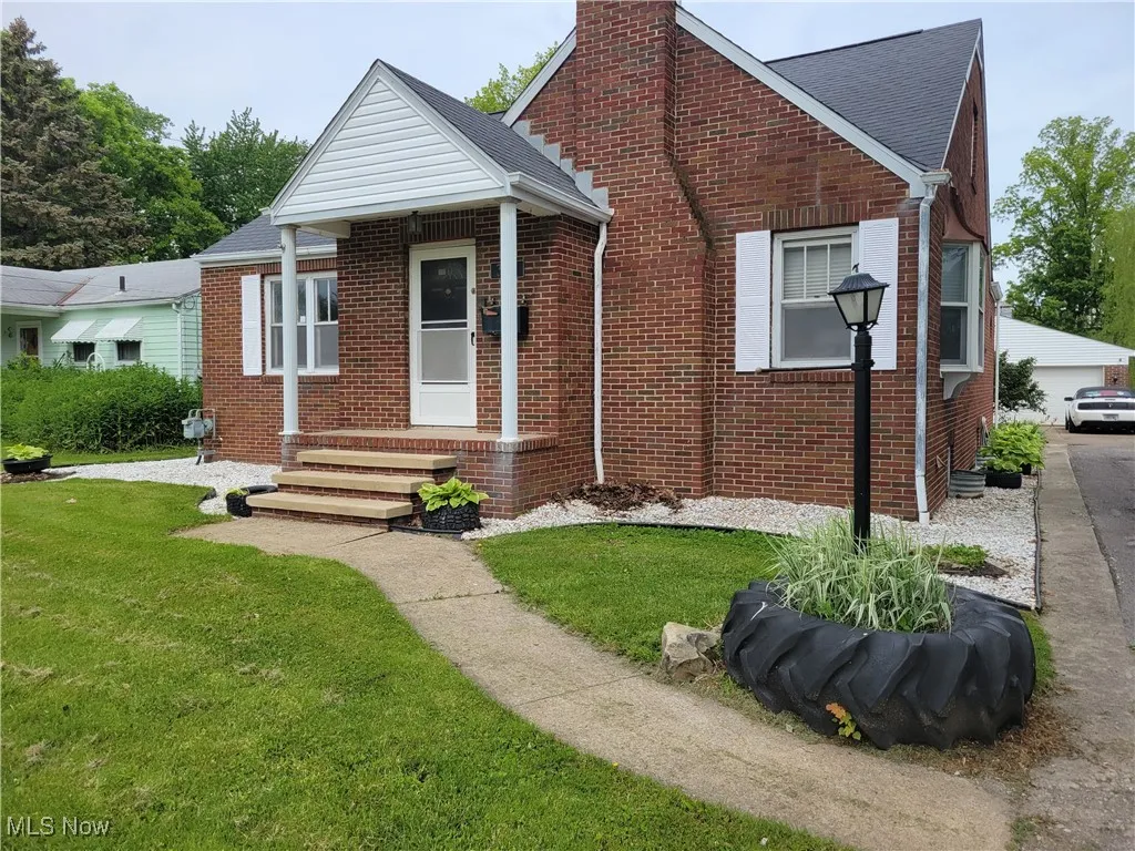 Bungalow with brick siding, a chimney, and a front lawn
