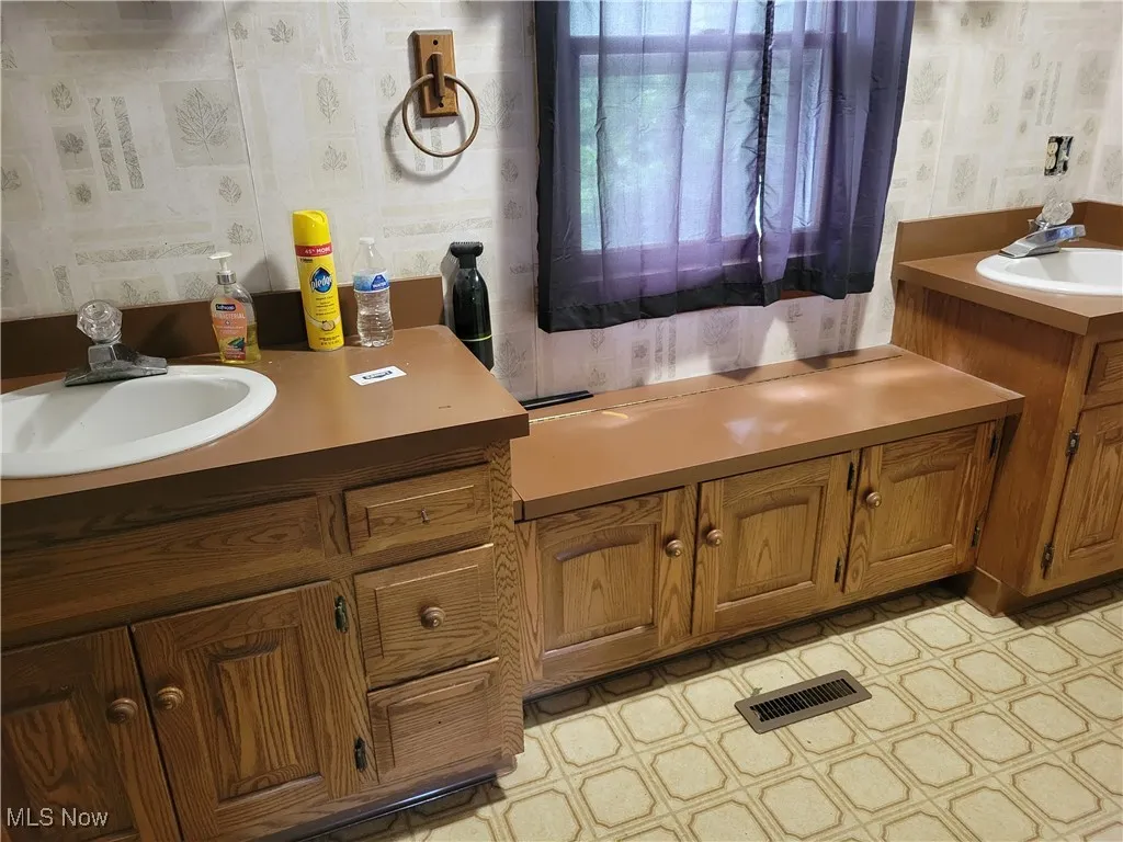 Bathroom featuring wallpapered walls and vanity