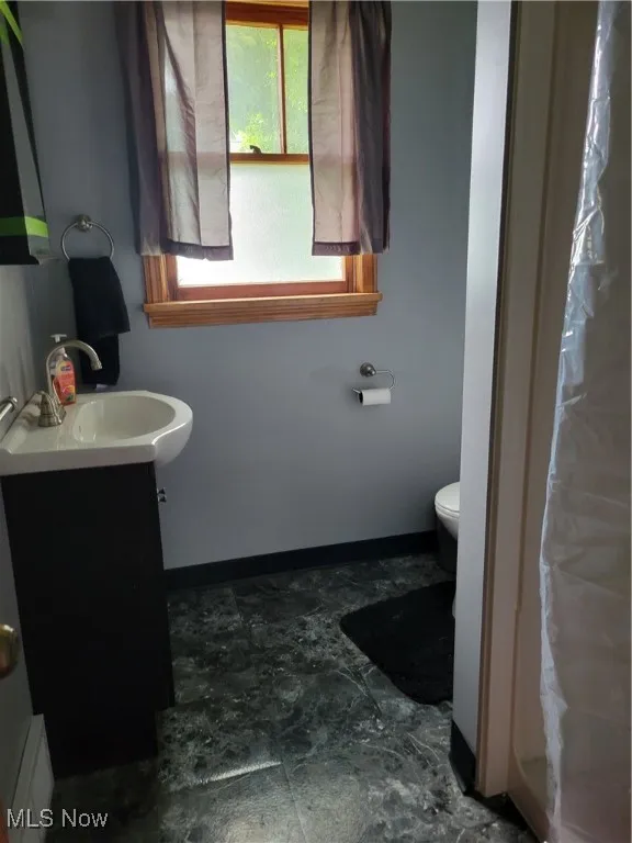 Bathroom with vanity, toilet, and baseboards