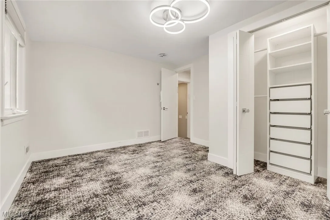 Unfurnished bedroom with carpet floors, baseboards, a closet, and a chandelier