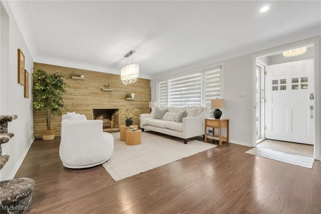 Living room with wood finished floors, baseboards, a fireplace, and recessed lighting