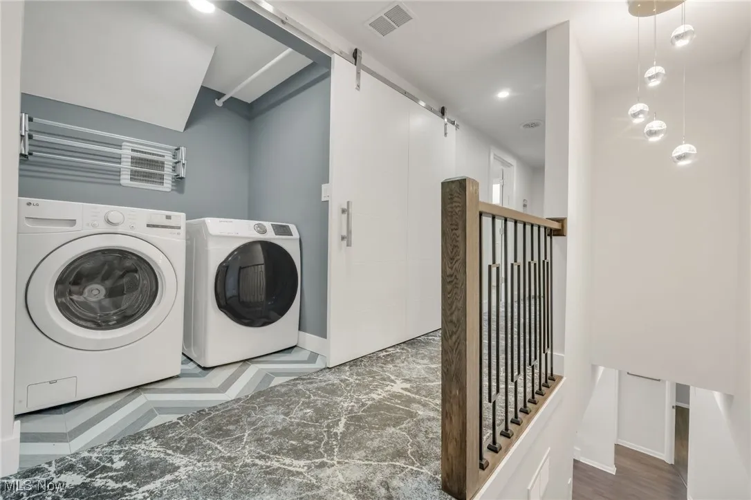Laundry area with a barn door, baseboards, washer and clothes dryer, and recessed lighting