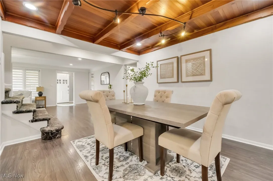 Dining room with wooden ceiling with exposed beams, wood finished floors, baseboards, and recessed lighting