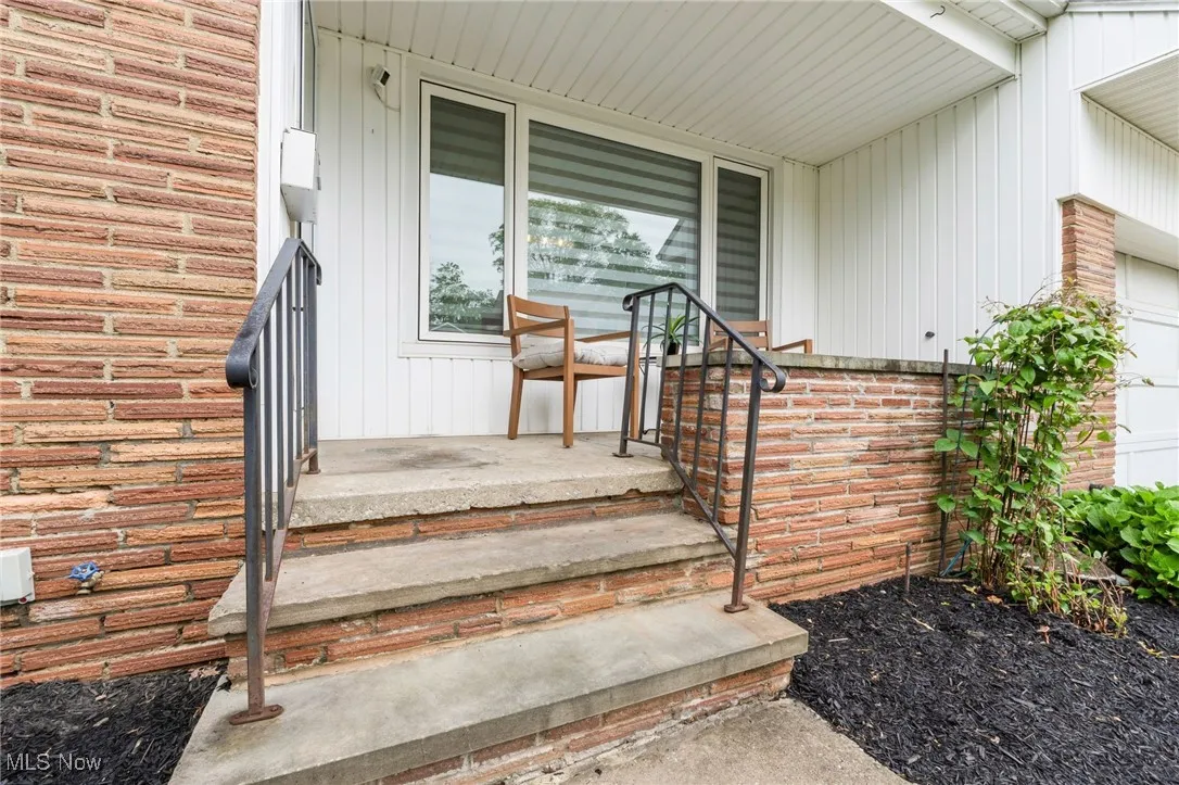 Property entrance with brick siding, board and batten siding, and an attached garage