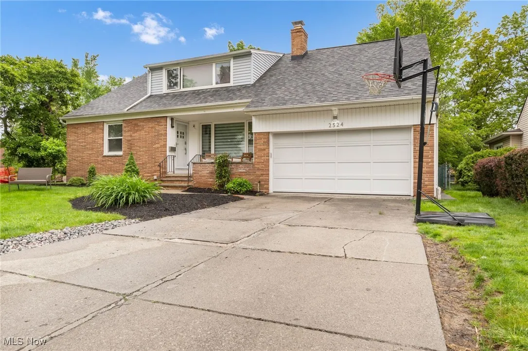 Traditional home featuring brick siding, a shingled roof, and a garage