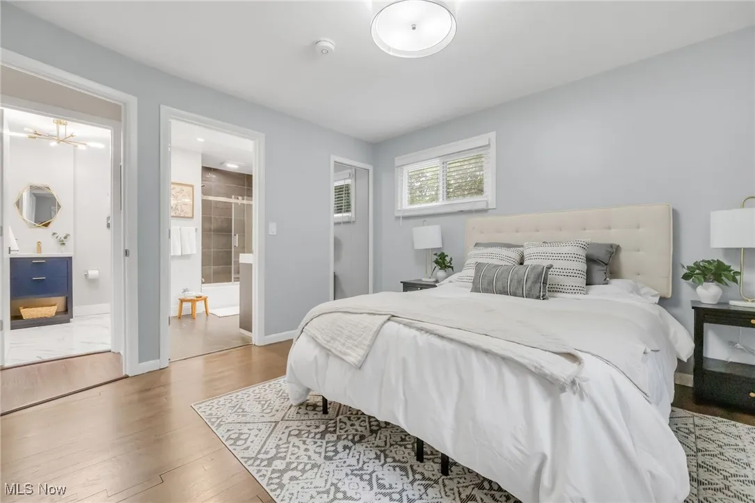 Bedroom with wood finished floors, ensuite bath, and baseboards