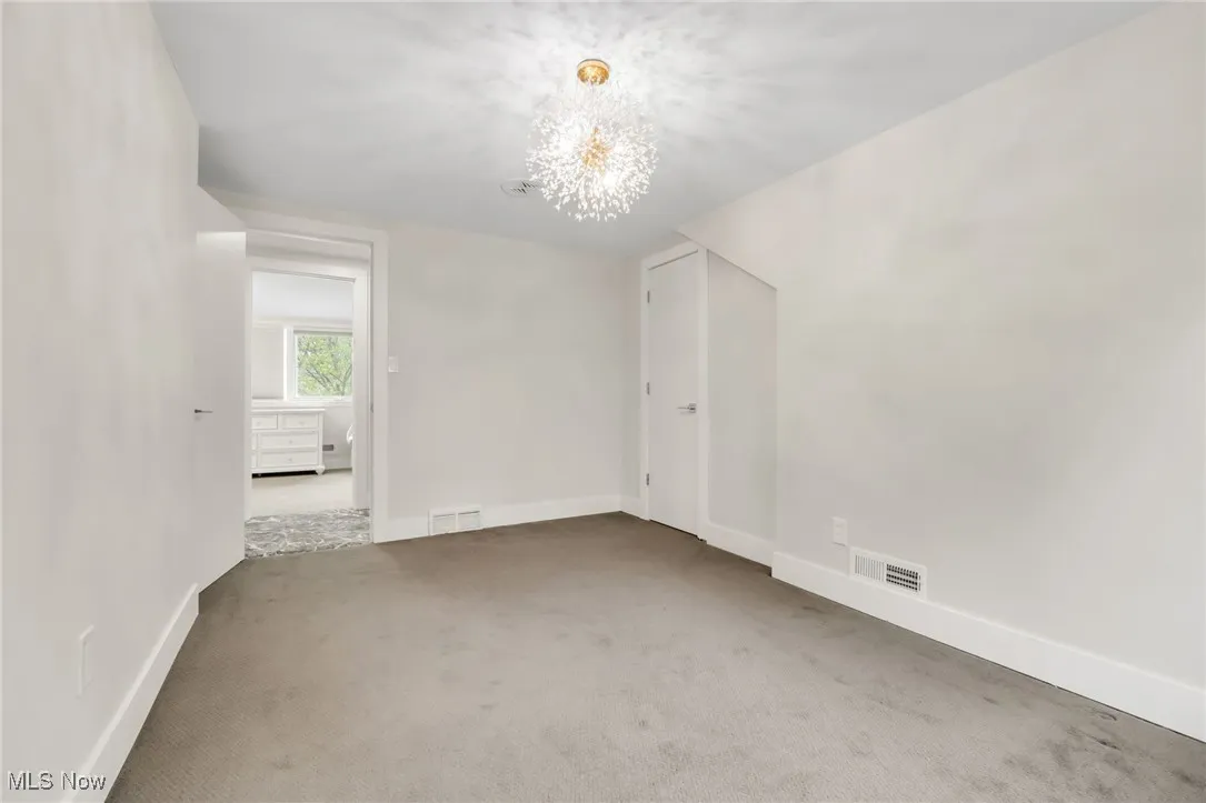 Unfurnished room with a chandelier, carpet floors, and baseboards