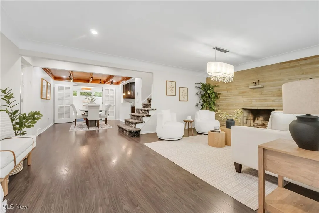 Living area with wood finished floors, baseboards, stairs, a fireplace, and ornamental molding
