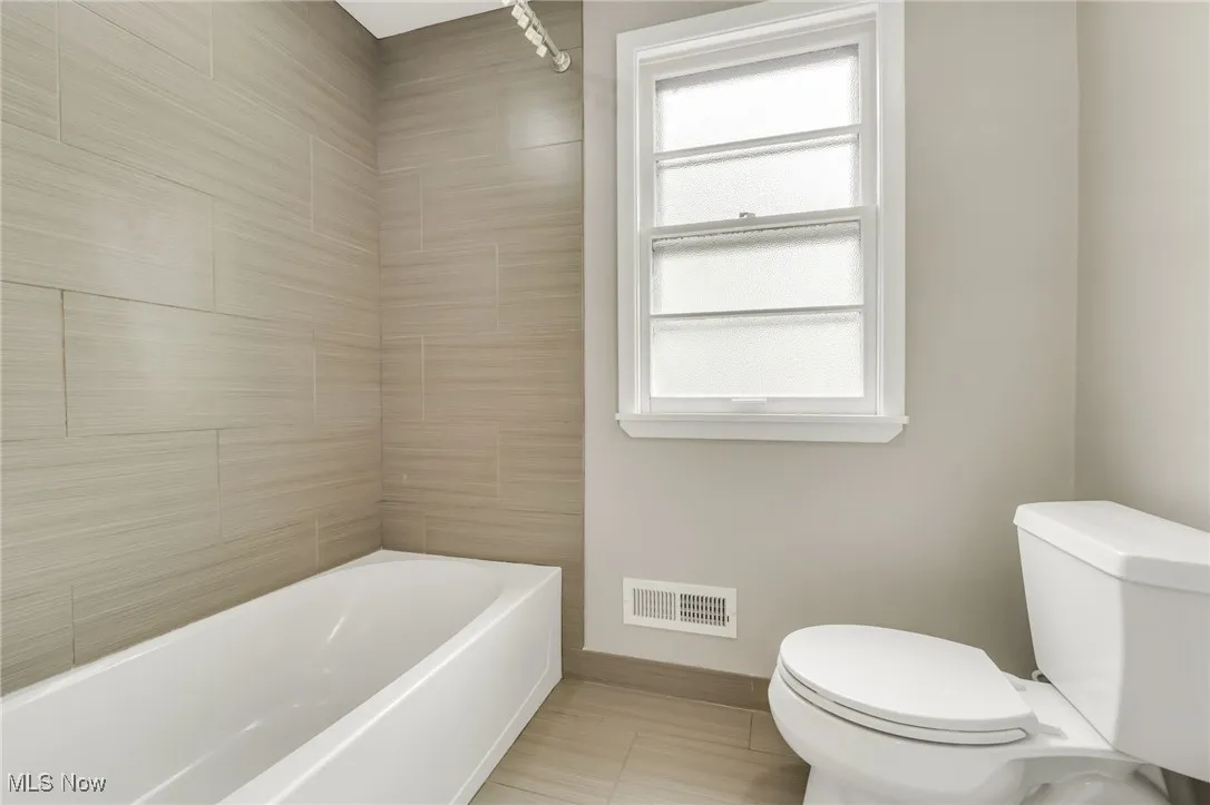 Bathroom featuring toilet, baseboards, and shower / bath combination