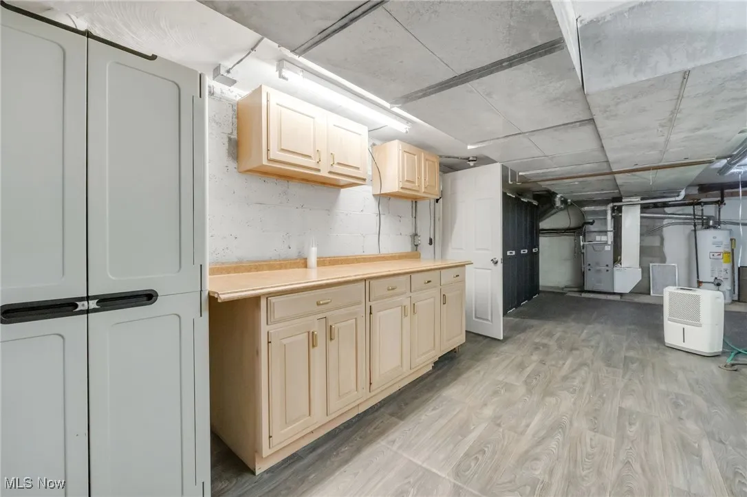 Below grade area featuring heating unit, light wood-style flooring, and gas water heater