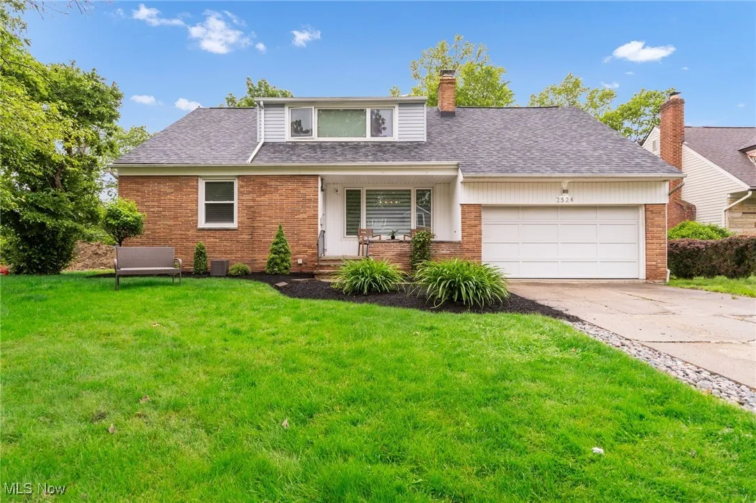 View of front facade with a front yard, brick siding, concrete driveway, and a garage
