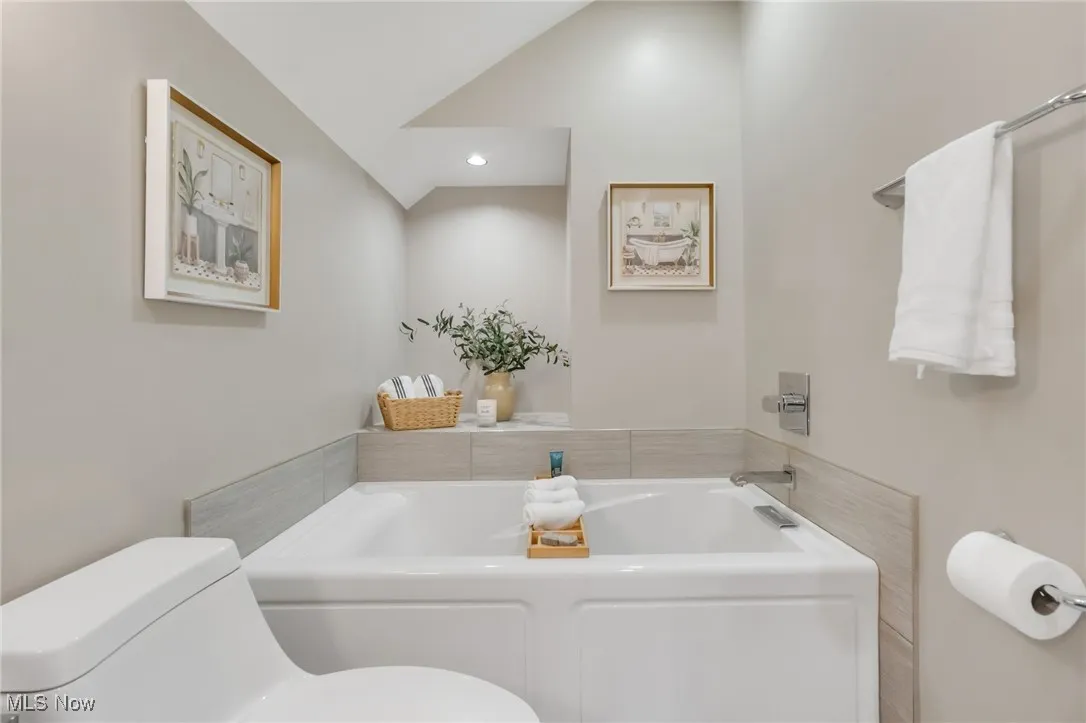Bathroom featuring toilet, a garden tub, vaulted ceiling, and recessed lighting
