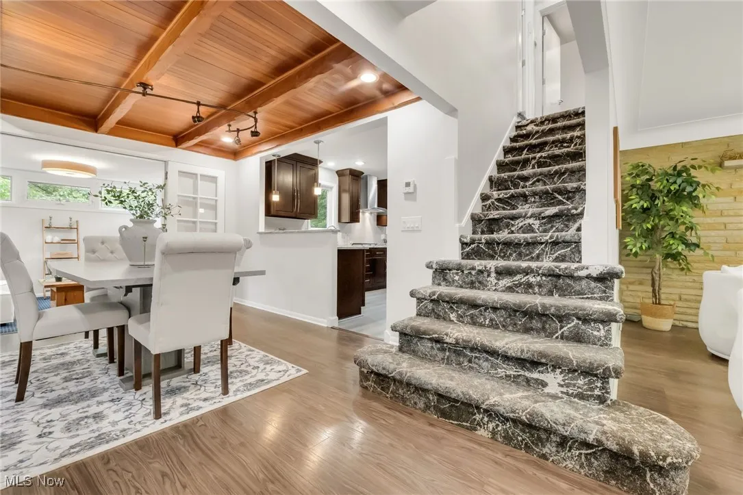 Dining room featuring wood ceiling with exposed beams, stairs, wood finished floors, and plenty of natural light