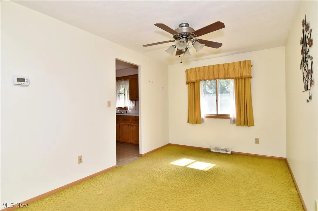 Unfurnished room with light carpet, healthy amount of natural light, and ceiling fan