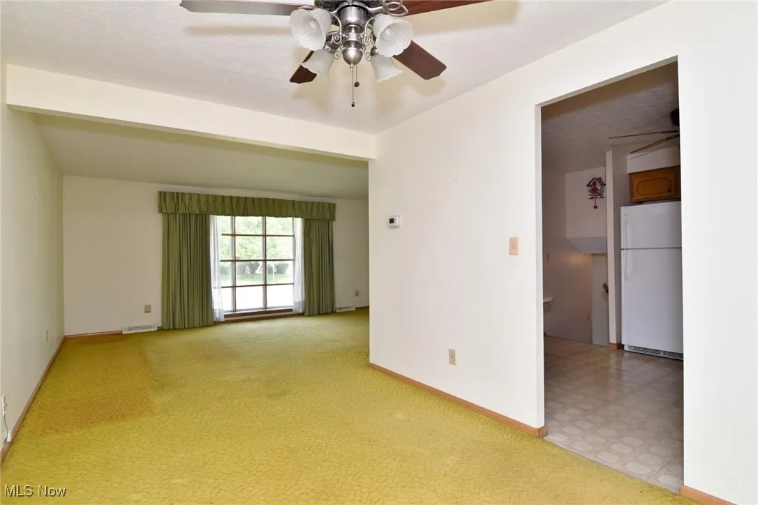 Spare room with a ceiling fan, baseboards, light floors, and light carpet